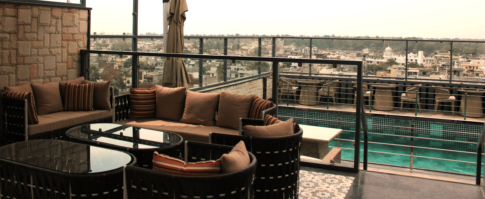 A rooftop lounge with a spacious patio and an adjacent swimming pool at BluSalzz Residence, Amritsar